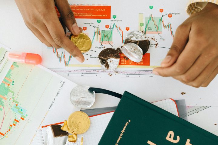 Person Holding a Gold Chocolate Coin on the Table with a Green Book